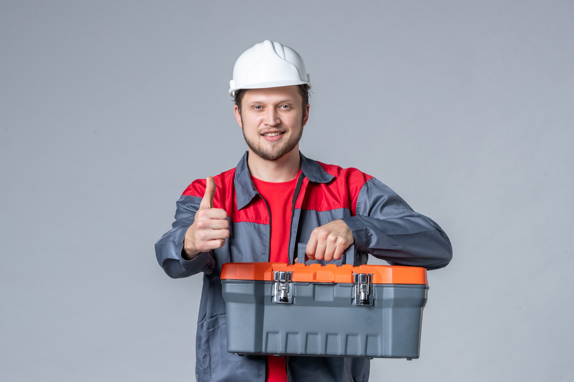 تعمیرکار اتو پرس که یک جعبه ابزار در دست گرفته است و ایستاده است.