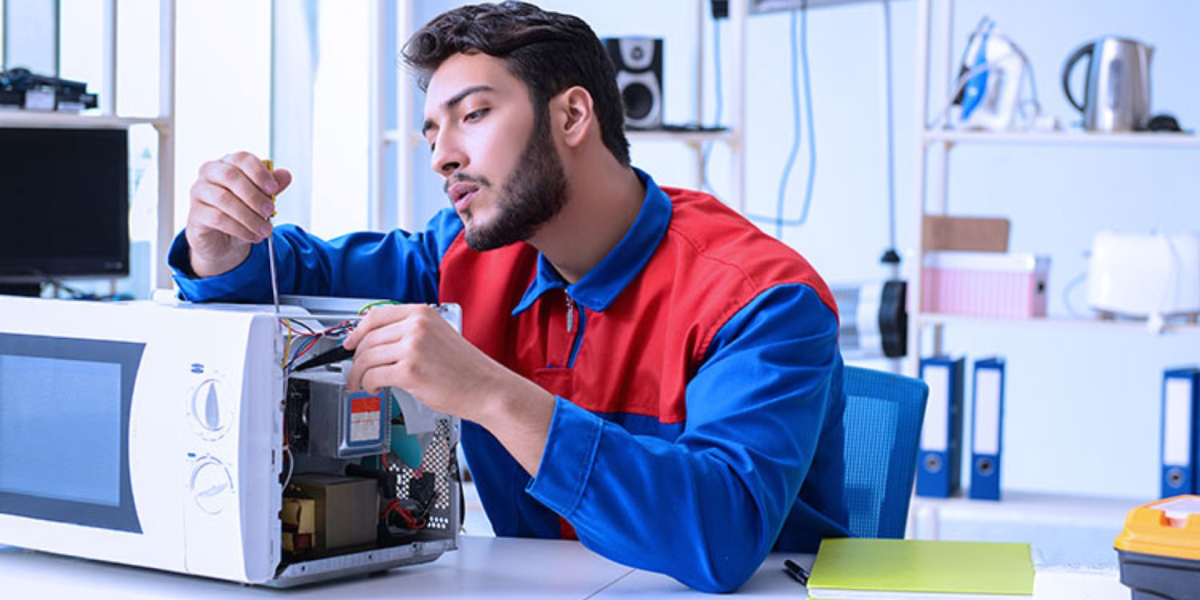 تعمیرکار ماکروفر درحال تعمیر و بررسی علائم خرابی ماکروفر