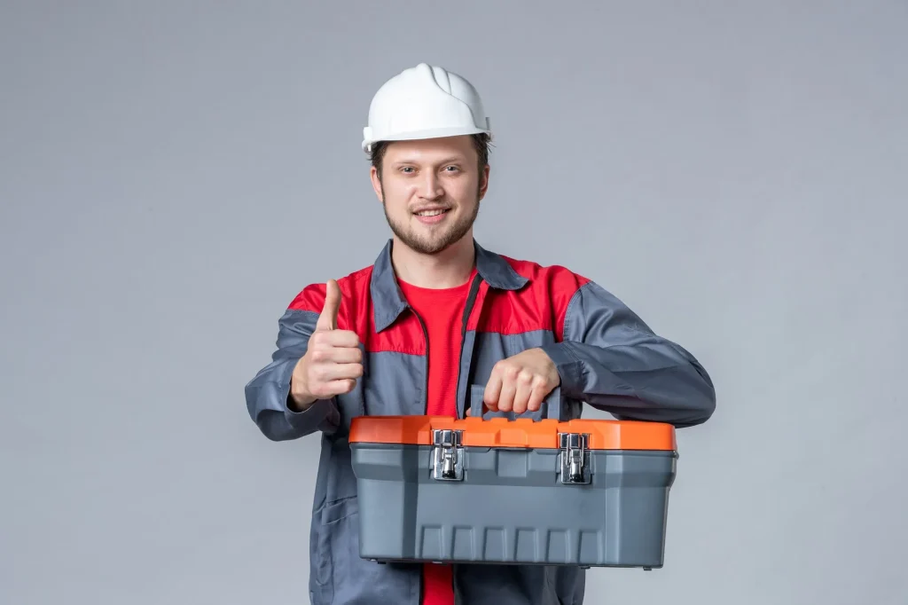 front view male builder uniform helmet holding tool case gray background 140725 147954